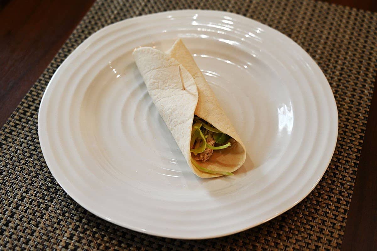 Costco Orowheat Keto Tortilla used to make a wrap rolled up and served on a white plate. 