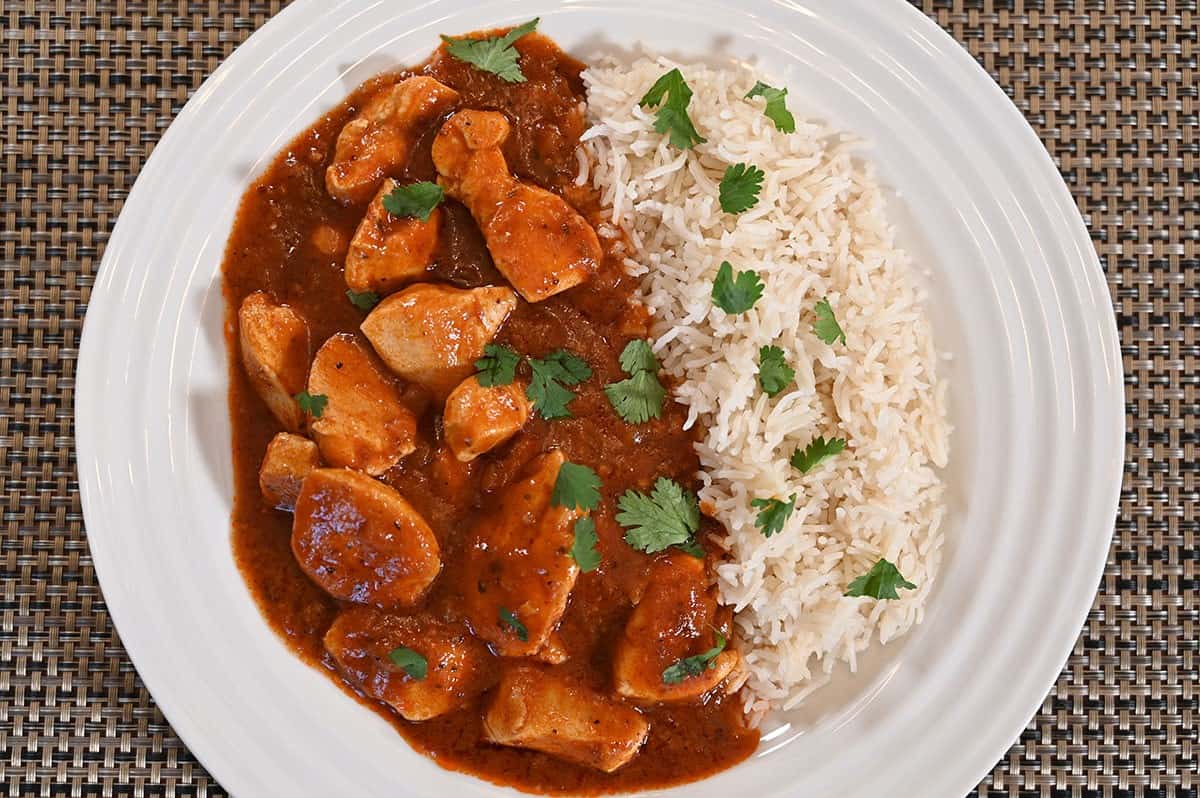 Plate of chicken vindaloo with rice prepared and on a white plate. 
