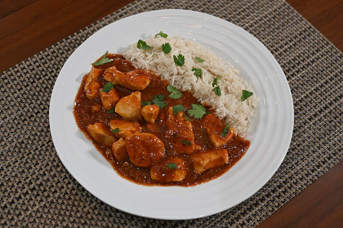 Plate of chicken vindaloo with rice prepared and on a white plate. 