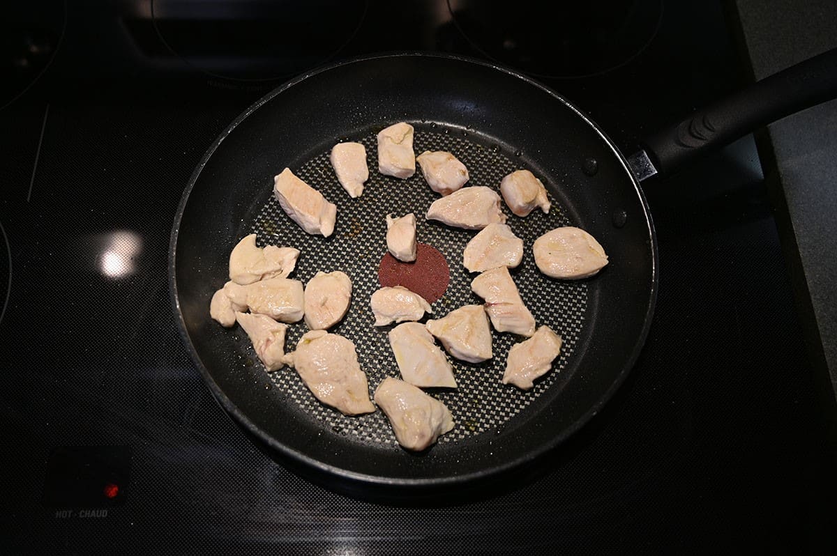 Image of cubes of chicken being cooked in a pan on the oven before adding vindaloo sauce. 
