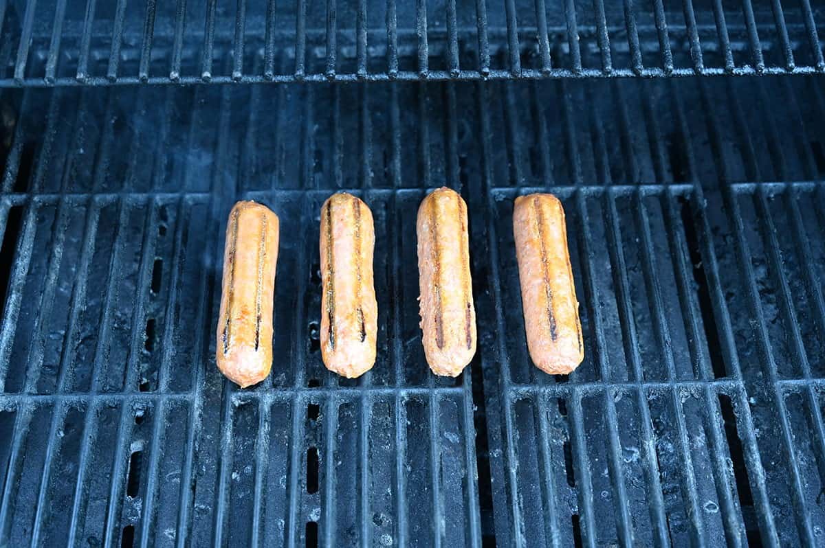 Four Costco Beyond Meat Beyond Sausages on a barbecue grilling.