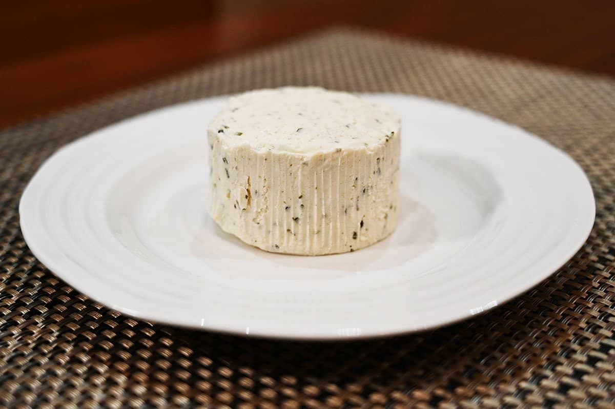 Image of unwrapped garlic & fine herbs Boursin cheese on a white plate. 