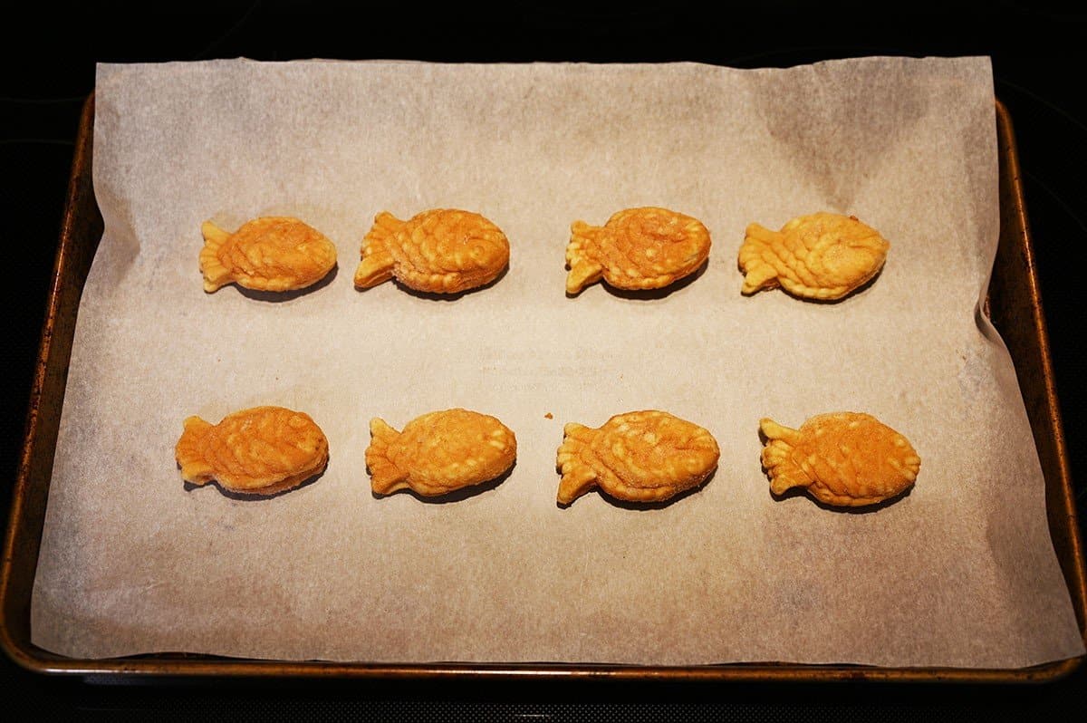 Image of taiyaki spread out on a cookie sheet cooking in the oven.