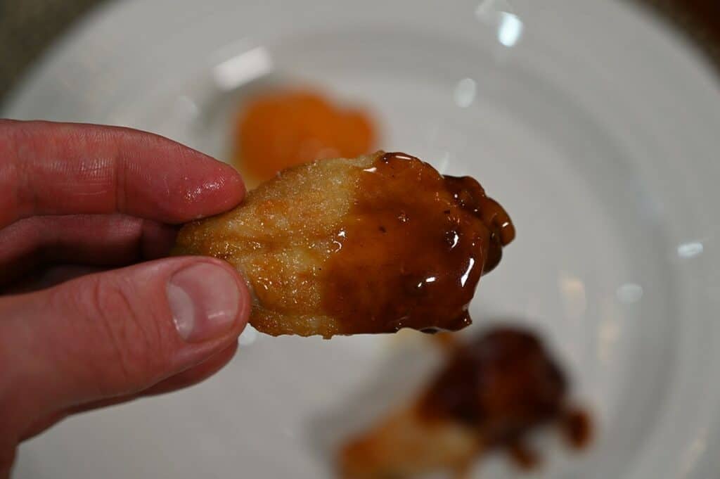 One Costco Pinty's Crispy Chicken Wing dipped in honey garlic sauce, closeup image. 