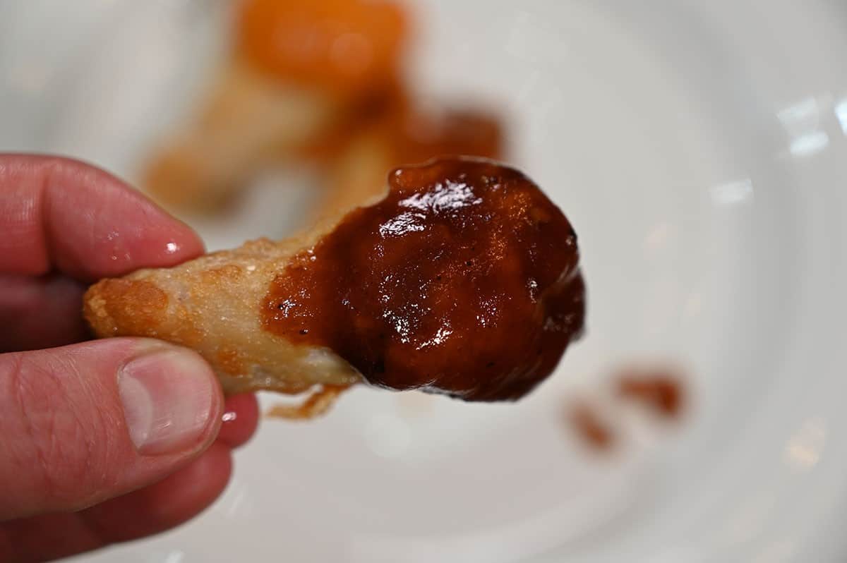 One Costco Pinty's Crispy Chicken Wing dipped in barbecue sauce, closeup image. 