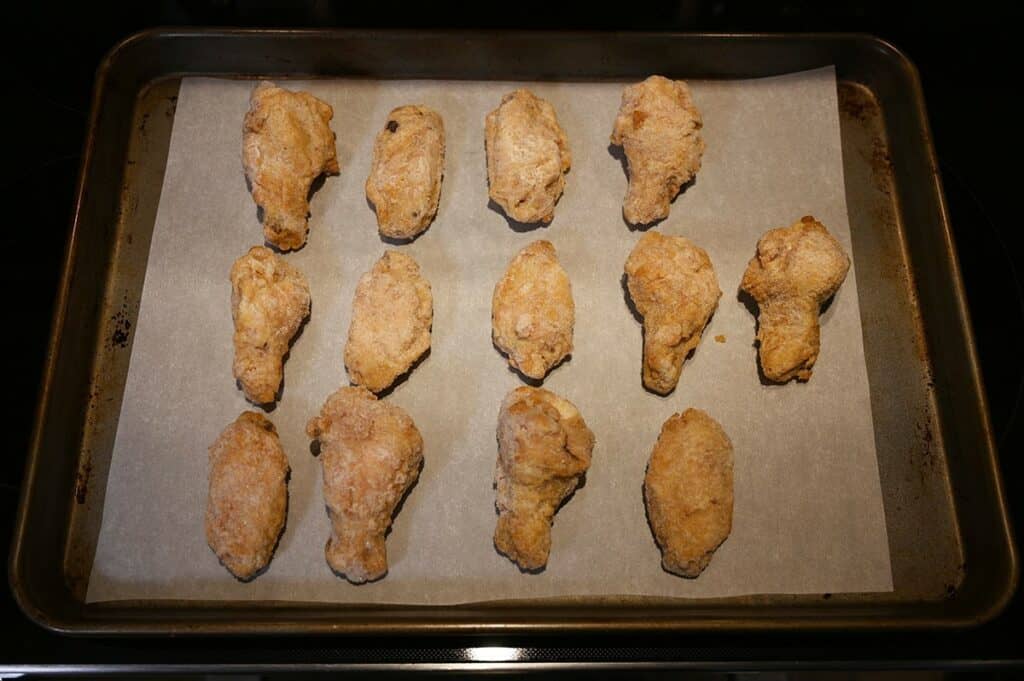 Image of the  wings cooking on a cookie sheet in the oven.