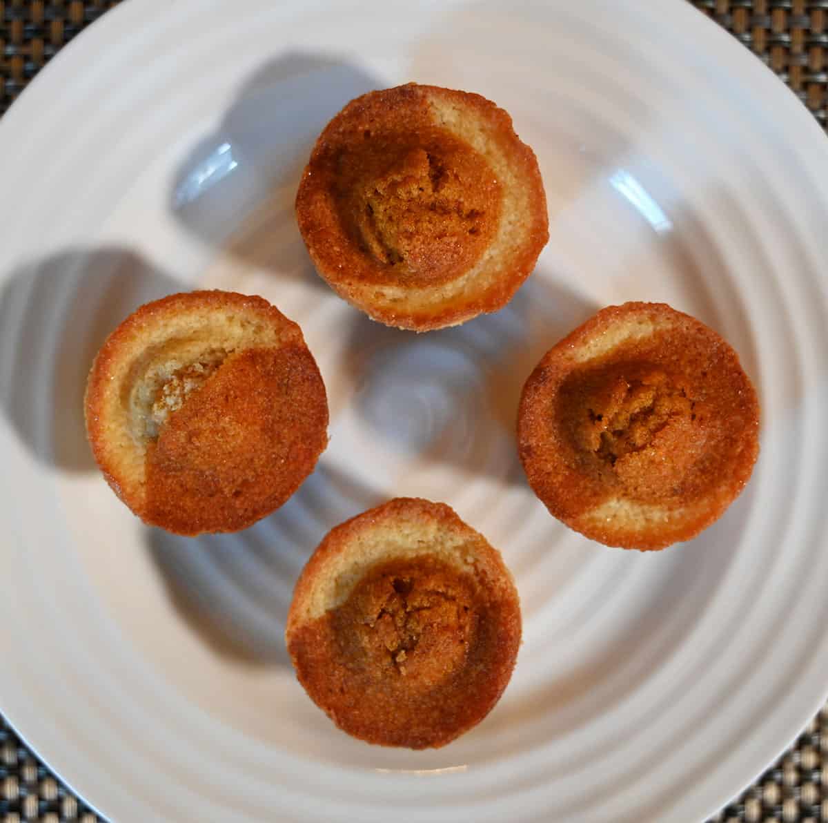 Four Costco Sugar Bowl Bakery Carrot Cake Bites on a white plate, top down image.