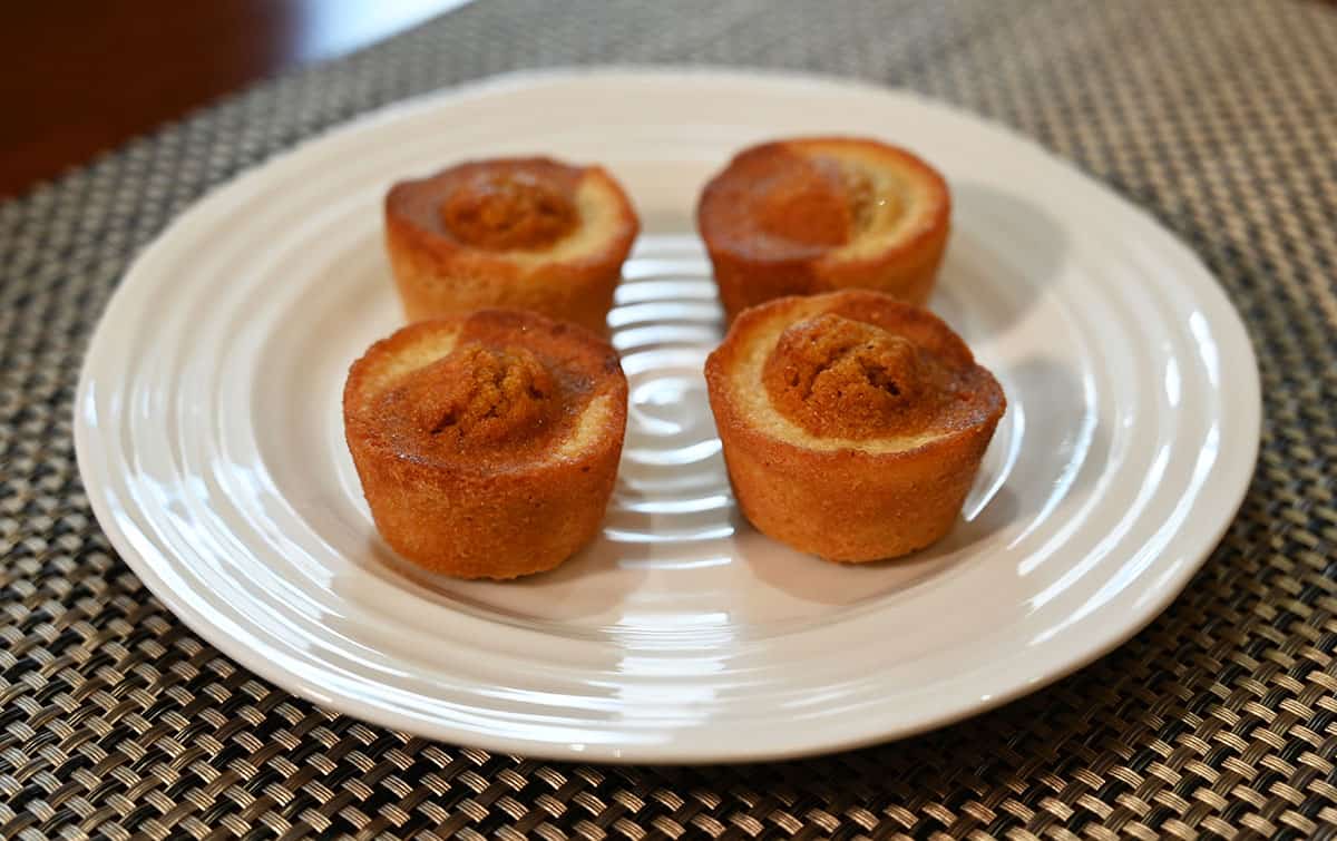 Four Costco Sugar Bowl Bakery Carrot Cake Bites on a white plate, side view image.