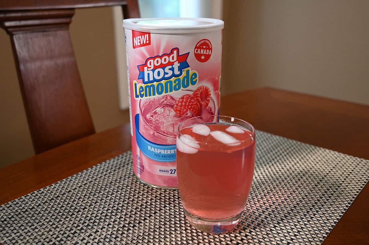 Costco Good Host Raspberry Lemonade container beside a prepared glass of lemonade on a table. 