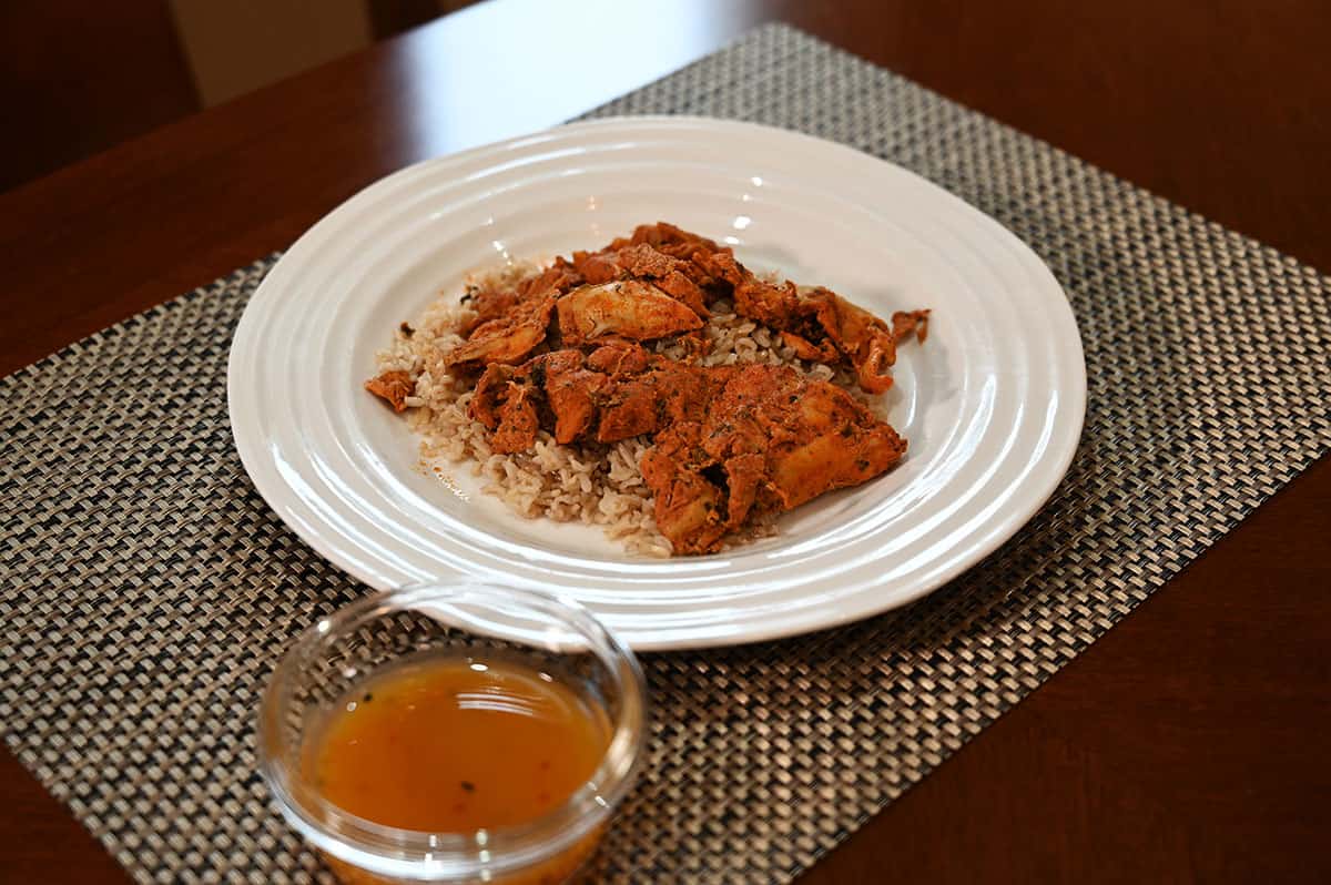 Costco Spice Mantra Tandoori Chicken cooked and served over rice on a white plate with mango chutney sauce in a small bowl on the side. 