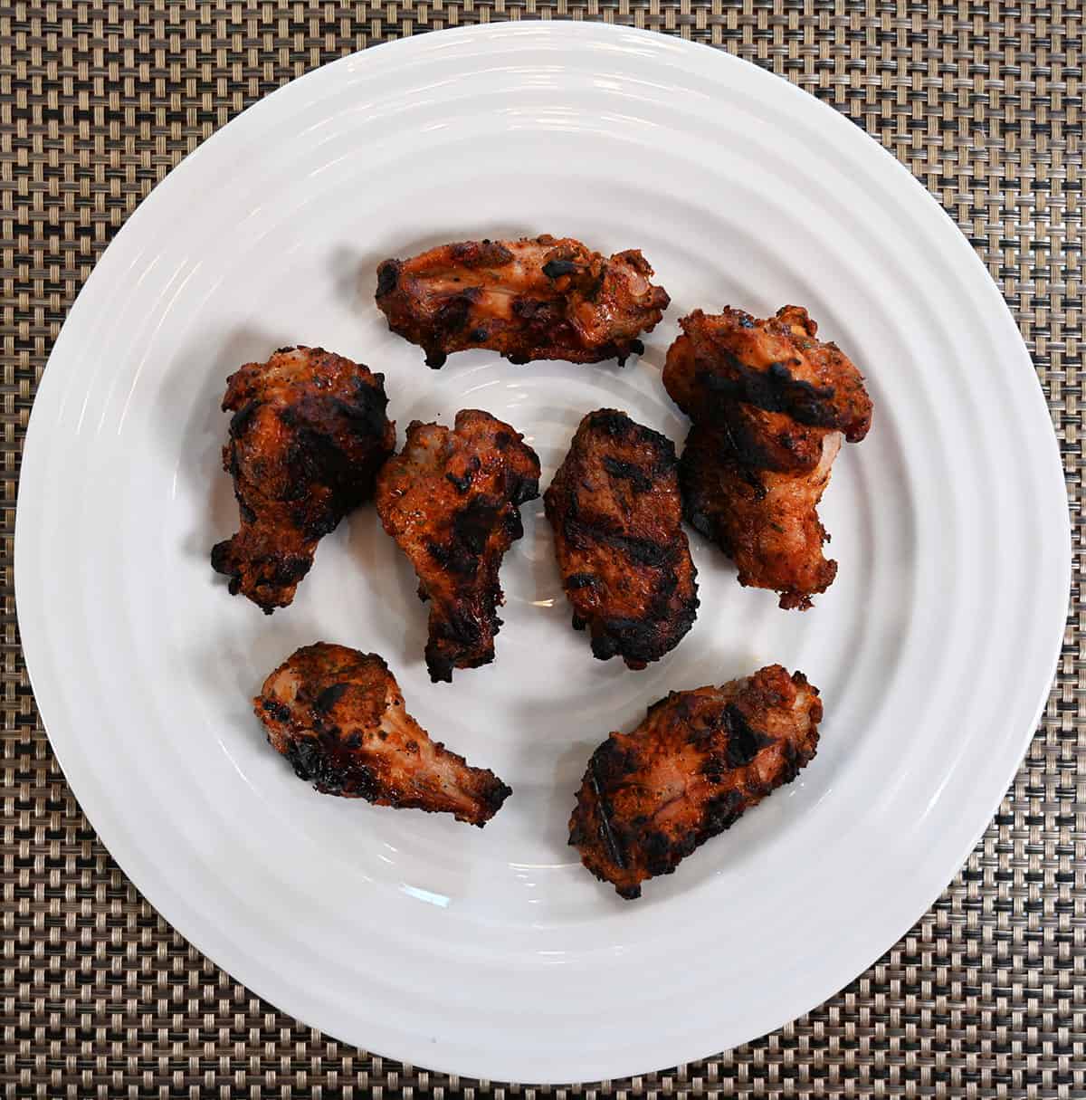 Plate of seven grilled Costco chicken wings, top down image.