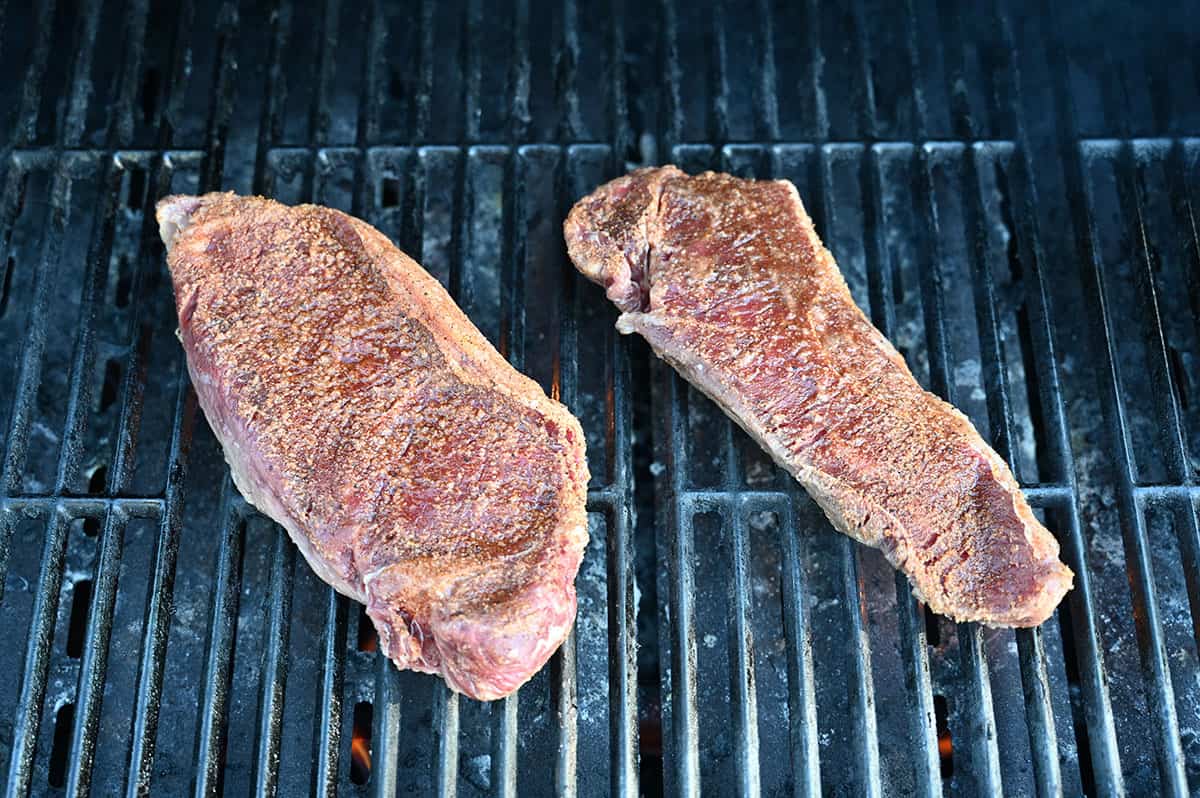 Image of two steaks on a barbecue being cooked with Hy's seasoning on them. 