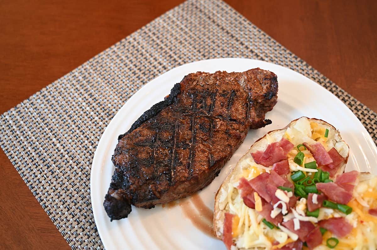 Image of a steak and baked potato on a white plate, steak has Hy's seasoning on it.