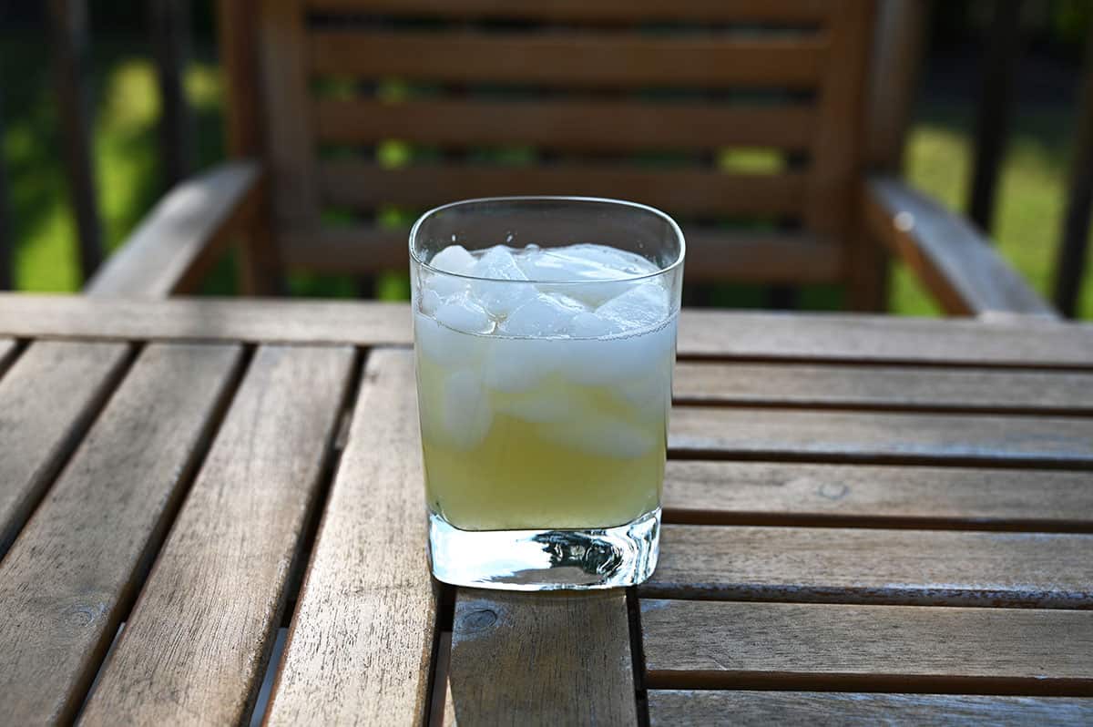 A glass of margarita sitting on a table on a deck outside.