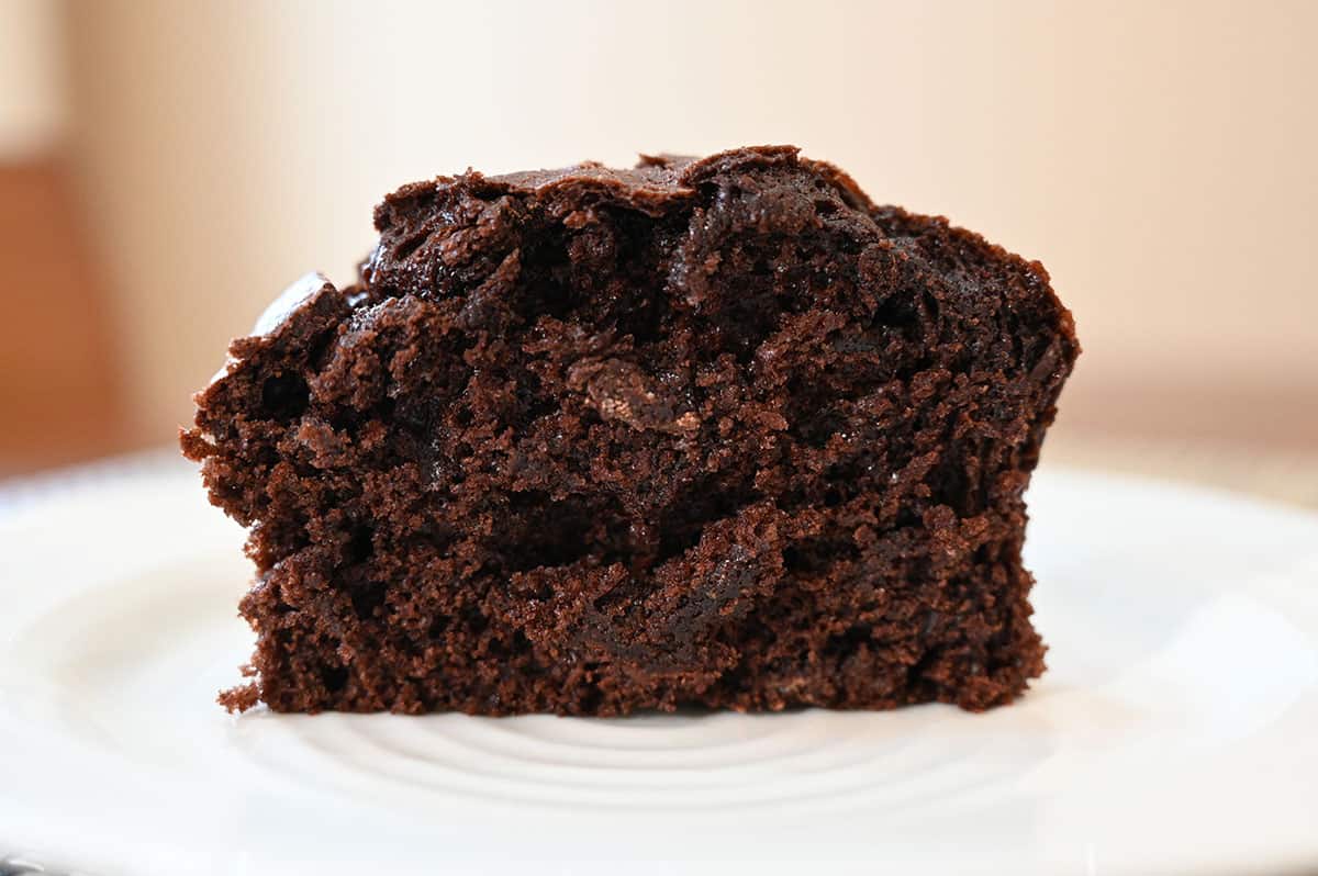 One Costco chocolate muffin cut in half on a white plate so you can see the middle.