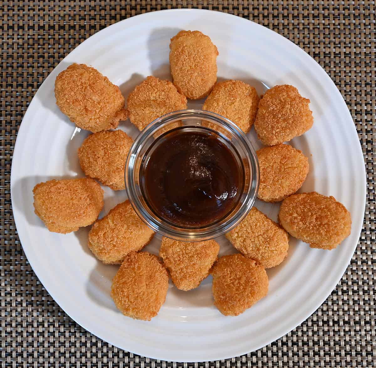 White plate with chicken nuggets on it and a dipping sauce in a bowl in the middle.