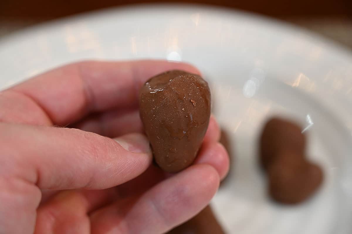 Closeup image of one Costco Tru Fru Frozen Chocolate Covered Strawberry with a plate full of them in the background.