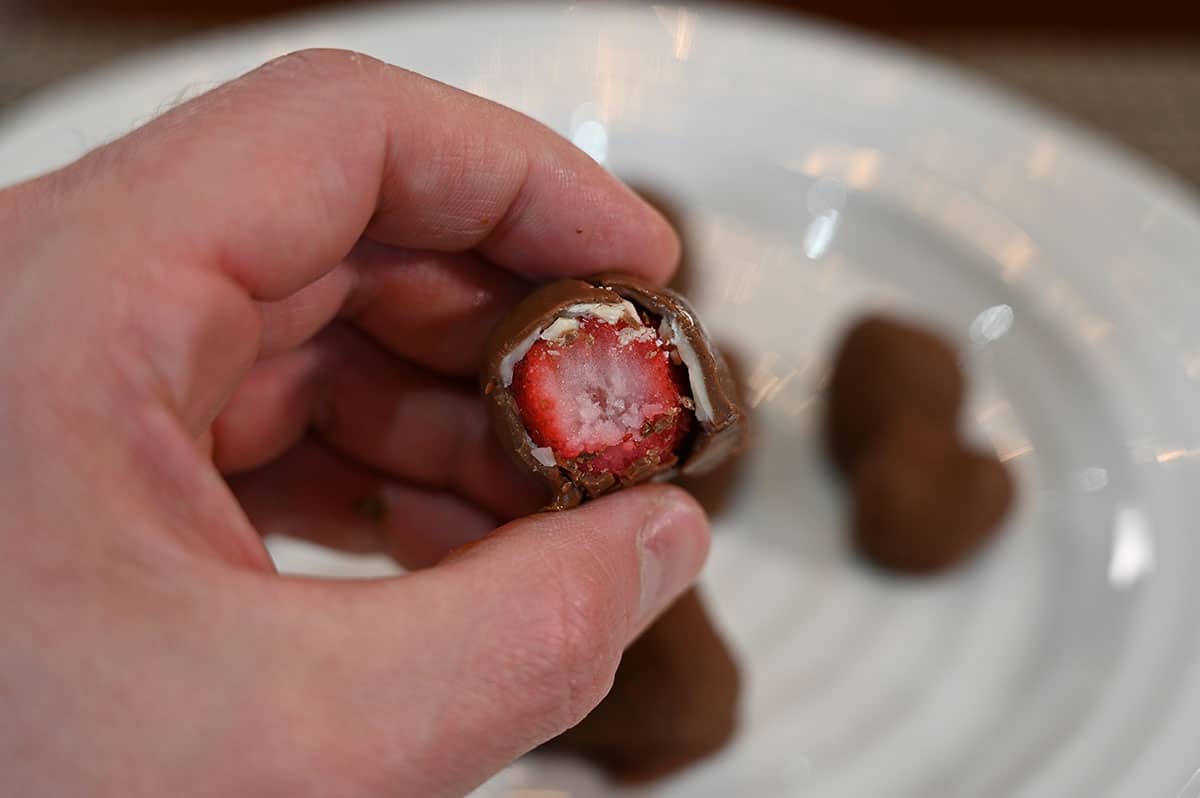 A closeup image of one Costco Tru Fru Frozen Chocolate Covered Strawberry with a bite taken out so you can see the inside.