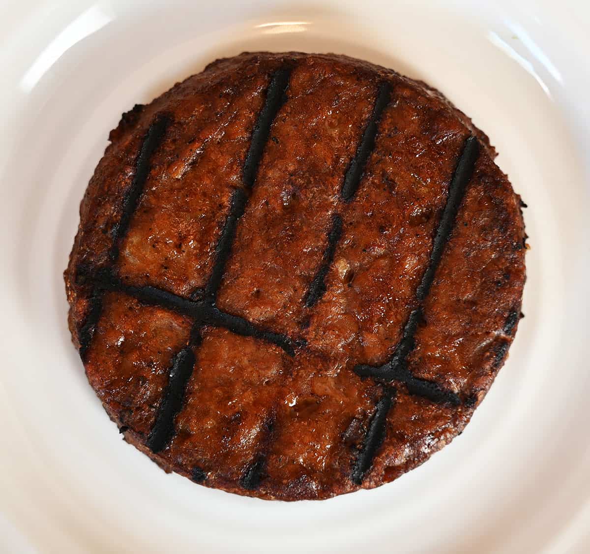 Closeup image of one patty, cooked and on a white plate.