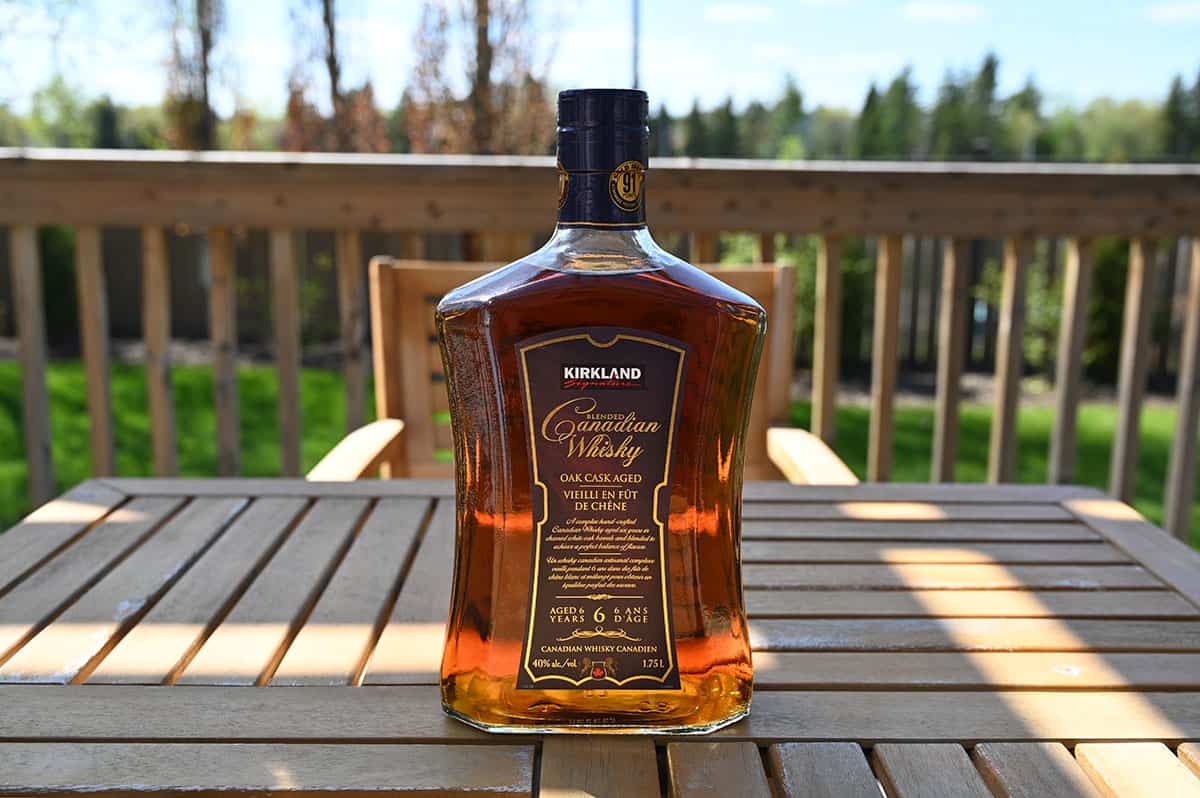 Image of the bottle of Kirkland Signature Blended Canadian Whisky on a table outside.