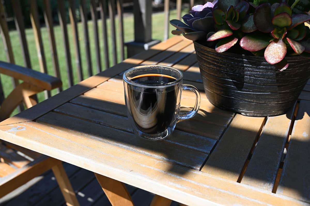 Image of a cup of brewed coffee on a table outside.