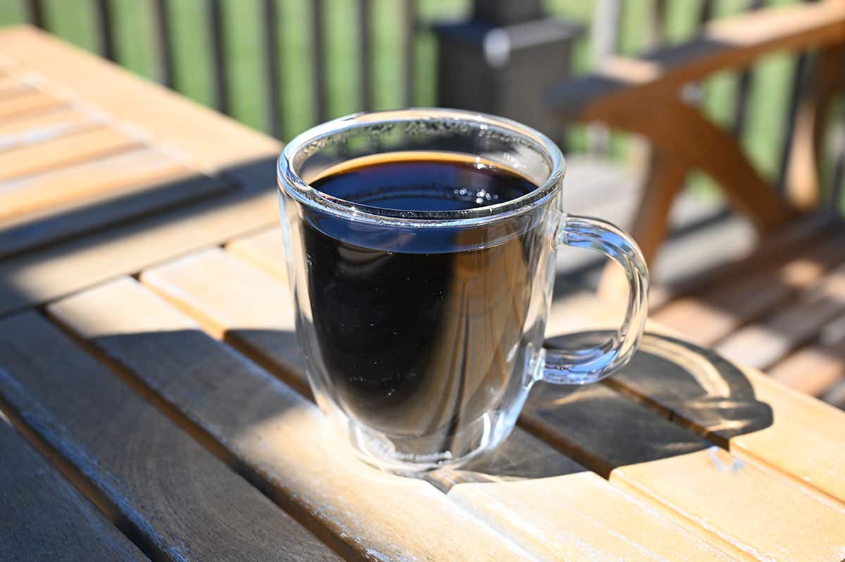 Closeup image of a cup of brewed coffee on a table outside.