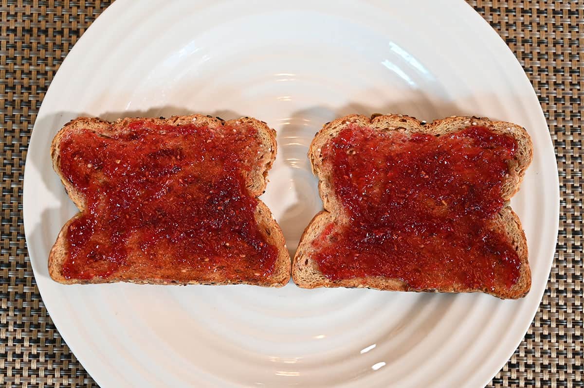 Image of two pieces of toast on a white plate with raspberry jam on top.