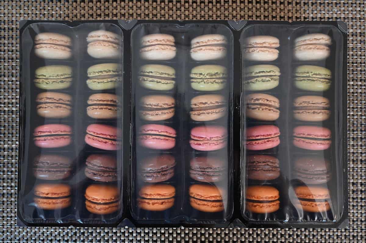 Image of the macaron packaging showing twelve macarons in each plastric tray with plastic wrap, two of each flavor per tray. 