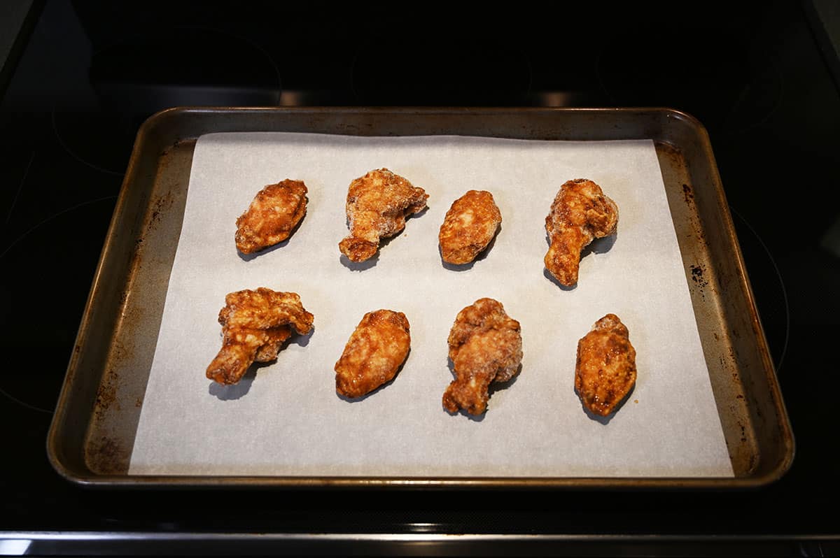 Image of wings on a cookie sheet being baked in the oven on parchment paper.