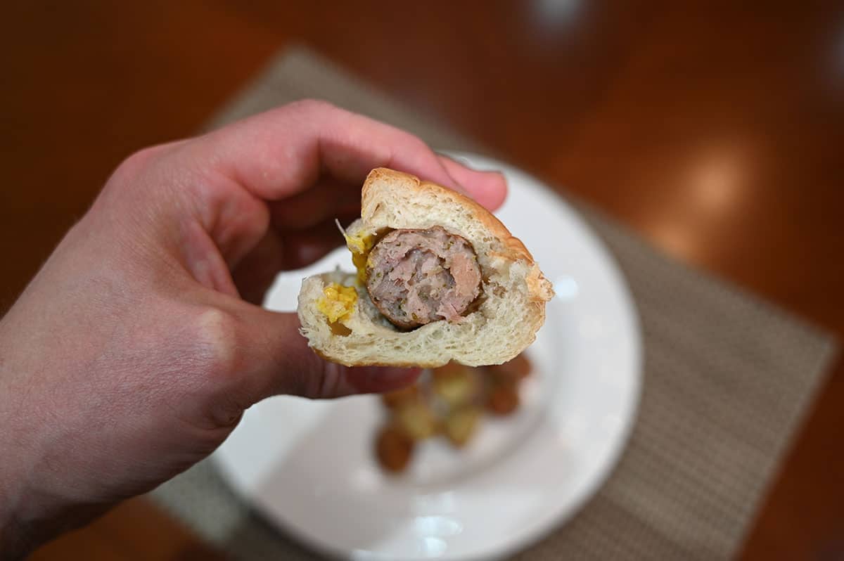 Closeup image of the sausage in a bun with a bite taken out of it so you can see the middle of the sausage.