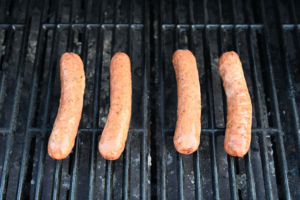 Four sausages being cooked on the grill.