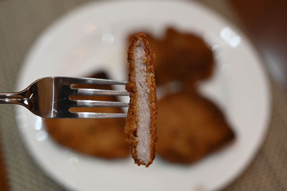 Closeup image of a piece of schnitzel cut in half so you can see the inside.