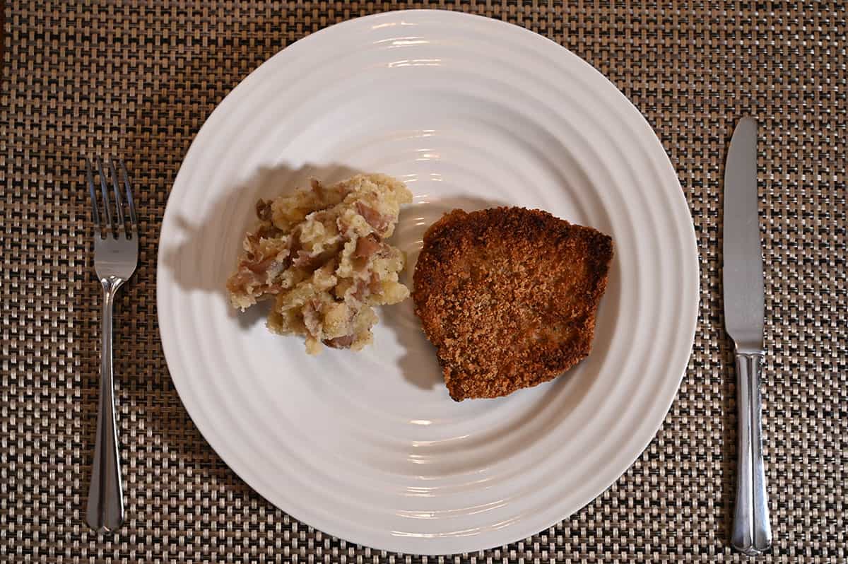 Top down image of a plate with one piece of schnitzel with mashed potatoes on the side.