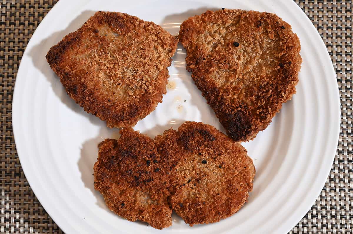 Top down image of three pieces of pork cooked and on a white plate.