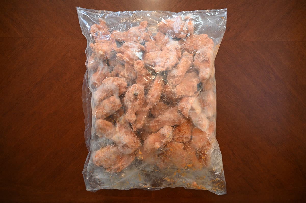 Plastic bag full of frozen chicken wings on a table.