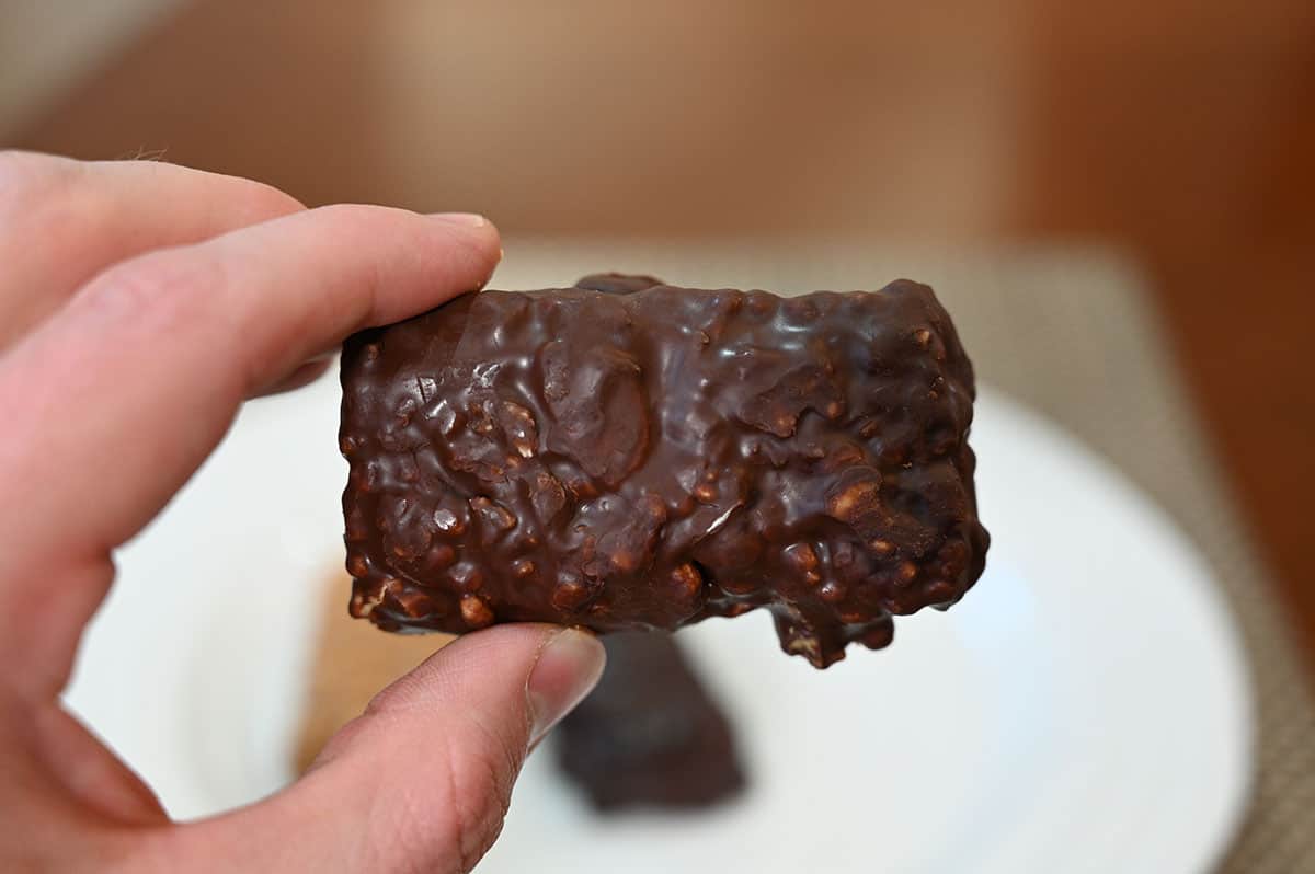 Closeup image of a hand holding the caramel almond bar.