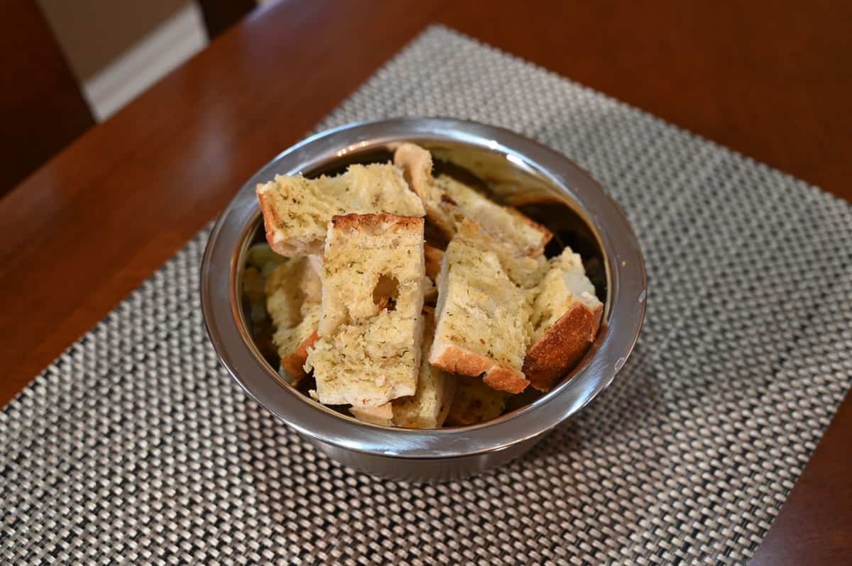 Image of a bowl of cut up baked garlic bread, ready to eat.