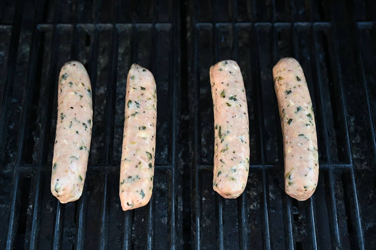 Closeup image of four sausages being barbecued.
