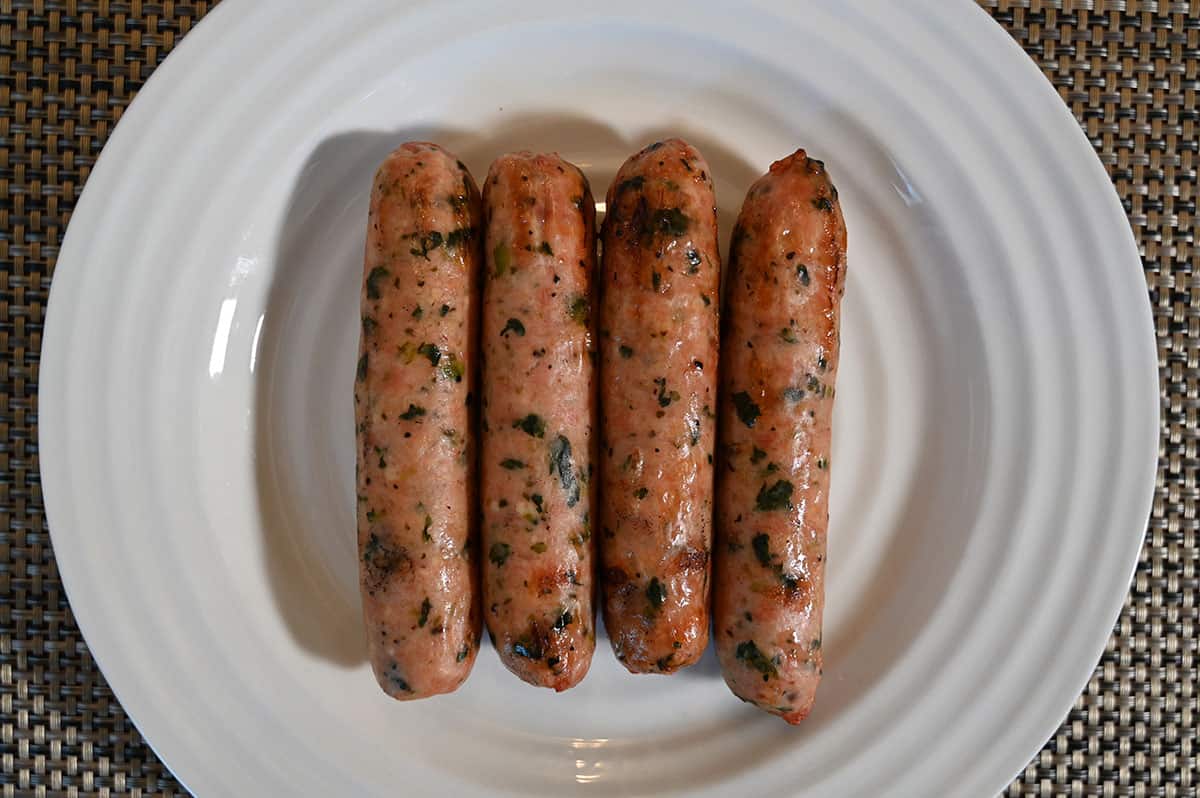 Closeup image of four cooked sausages on a white plate.