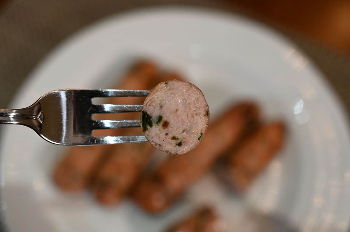 Closeup image of one bite of sausage cut so you can see the middle.