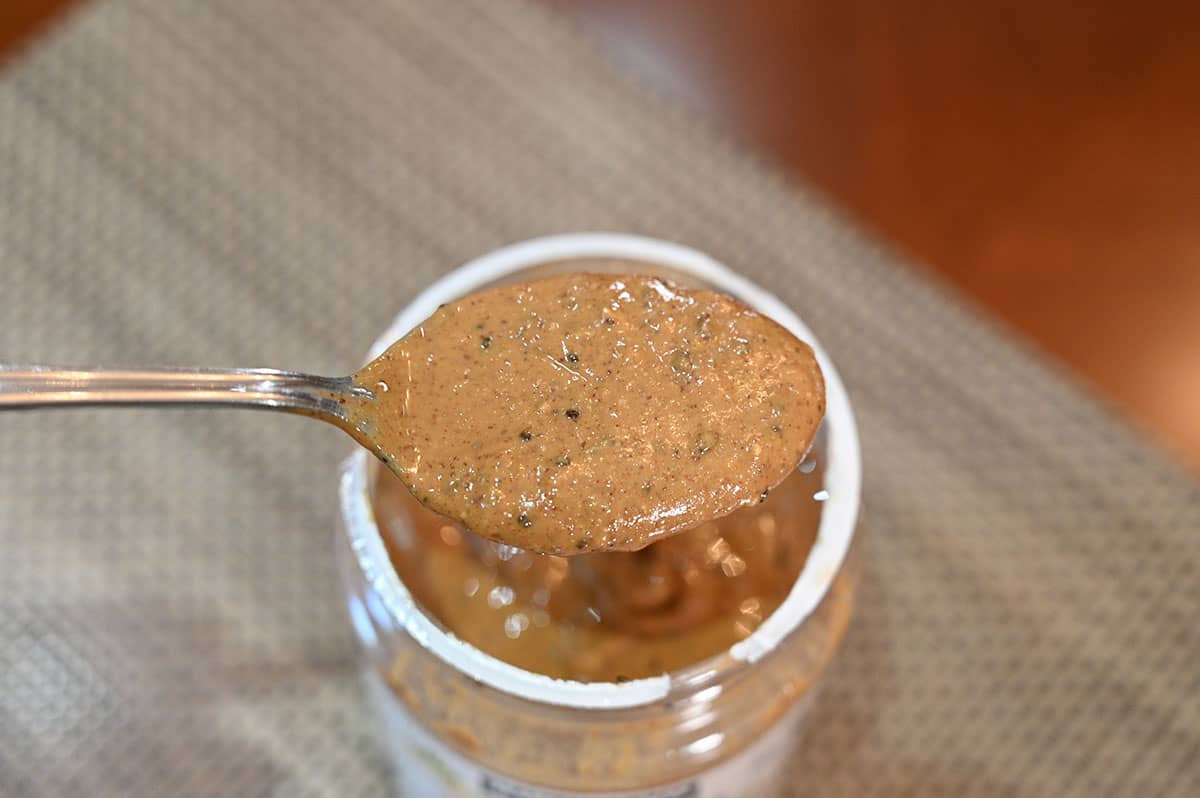Closeup image of a spoonful of nut butter overtop the jar.