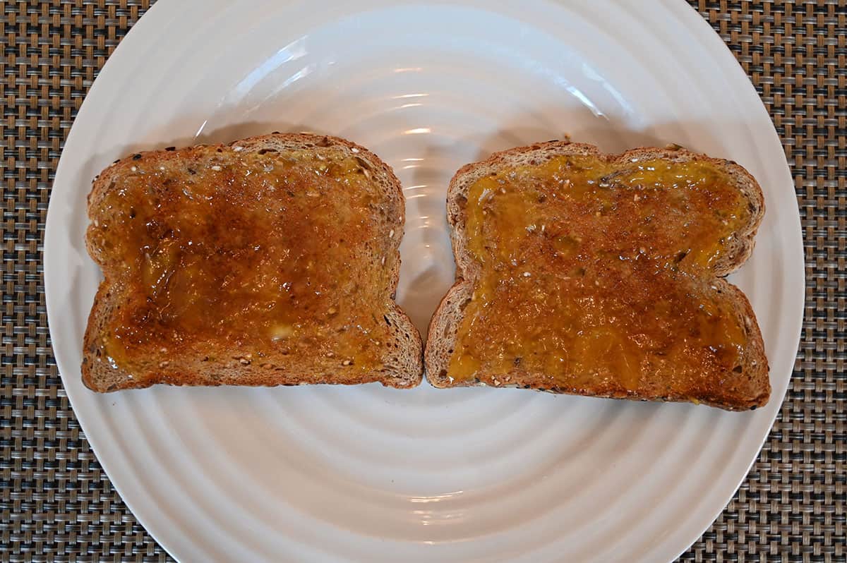 Image of two pieces of toast with spread on them served on a white plate.