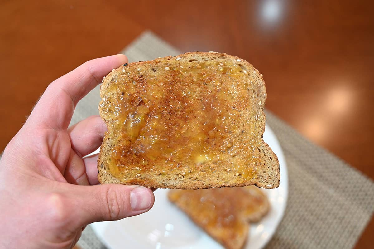 Image of a hand holding a piece of tast with spread on it.