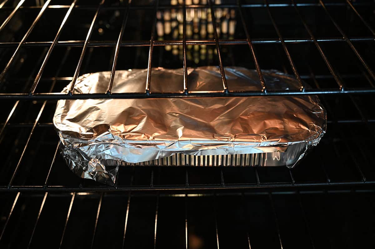 Image of the pork tenderloin tray with foil over it, cooking in the oven.