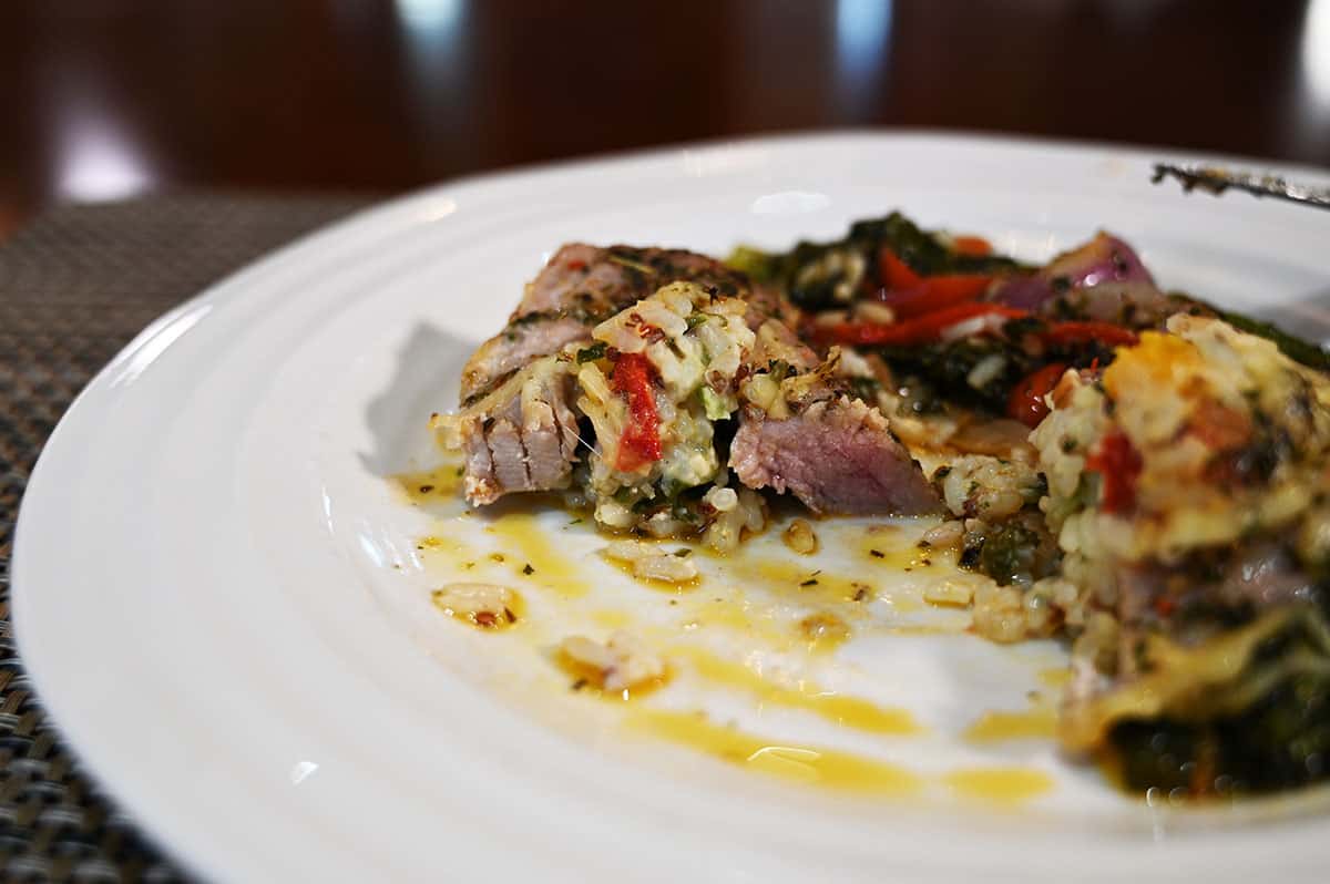 Side view image of the pork tenderloin meal on a white plate with bites taken from it.