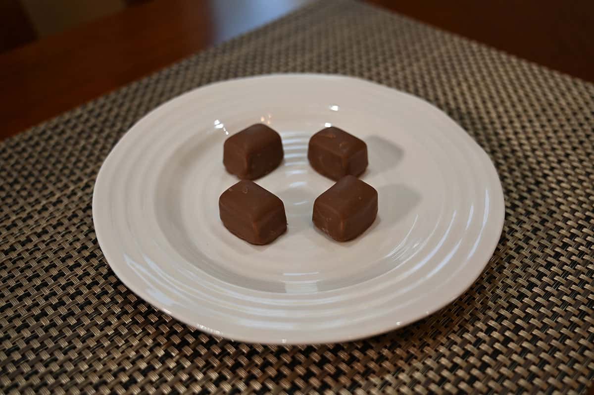 Sideview top down image of four mint milk chocolate truffles sitting on a white plate.