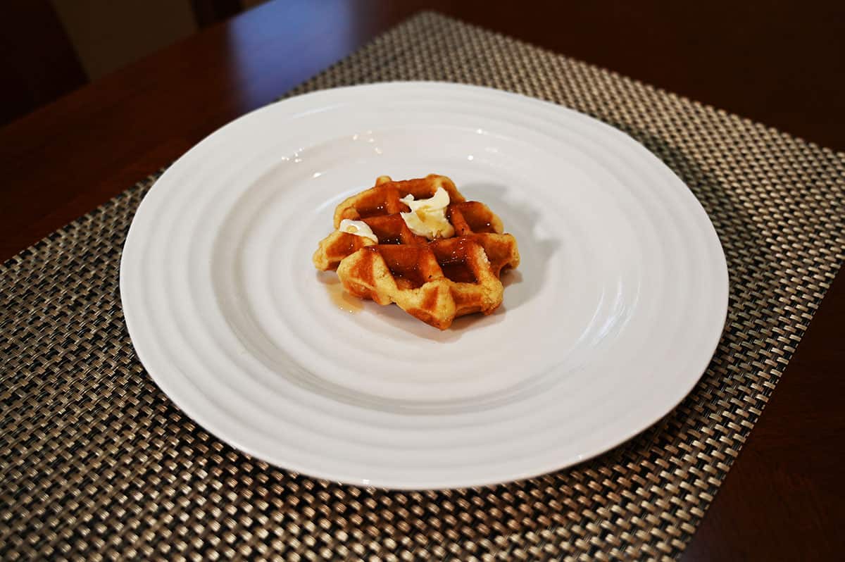 Image of one waffle out of the package on a white plate with butter on top.