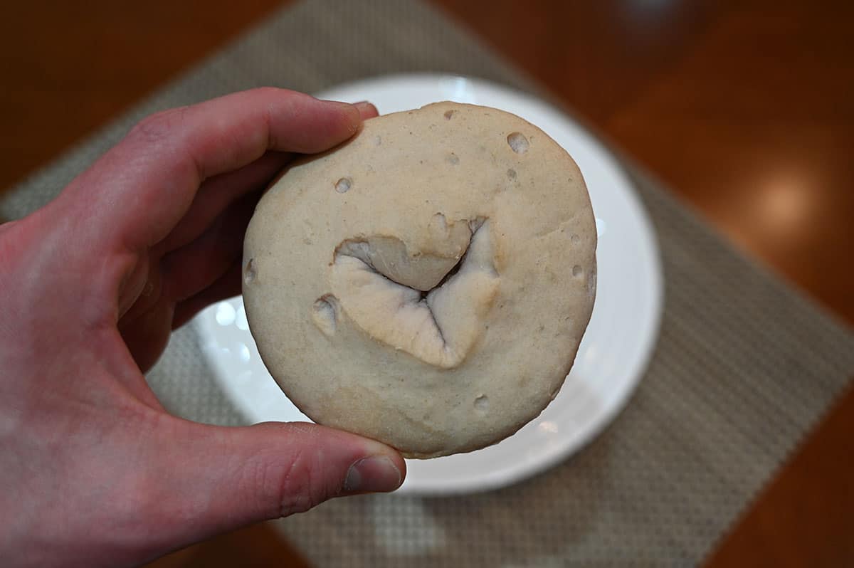 Closeup image of a hand holding one bagel.