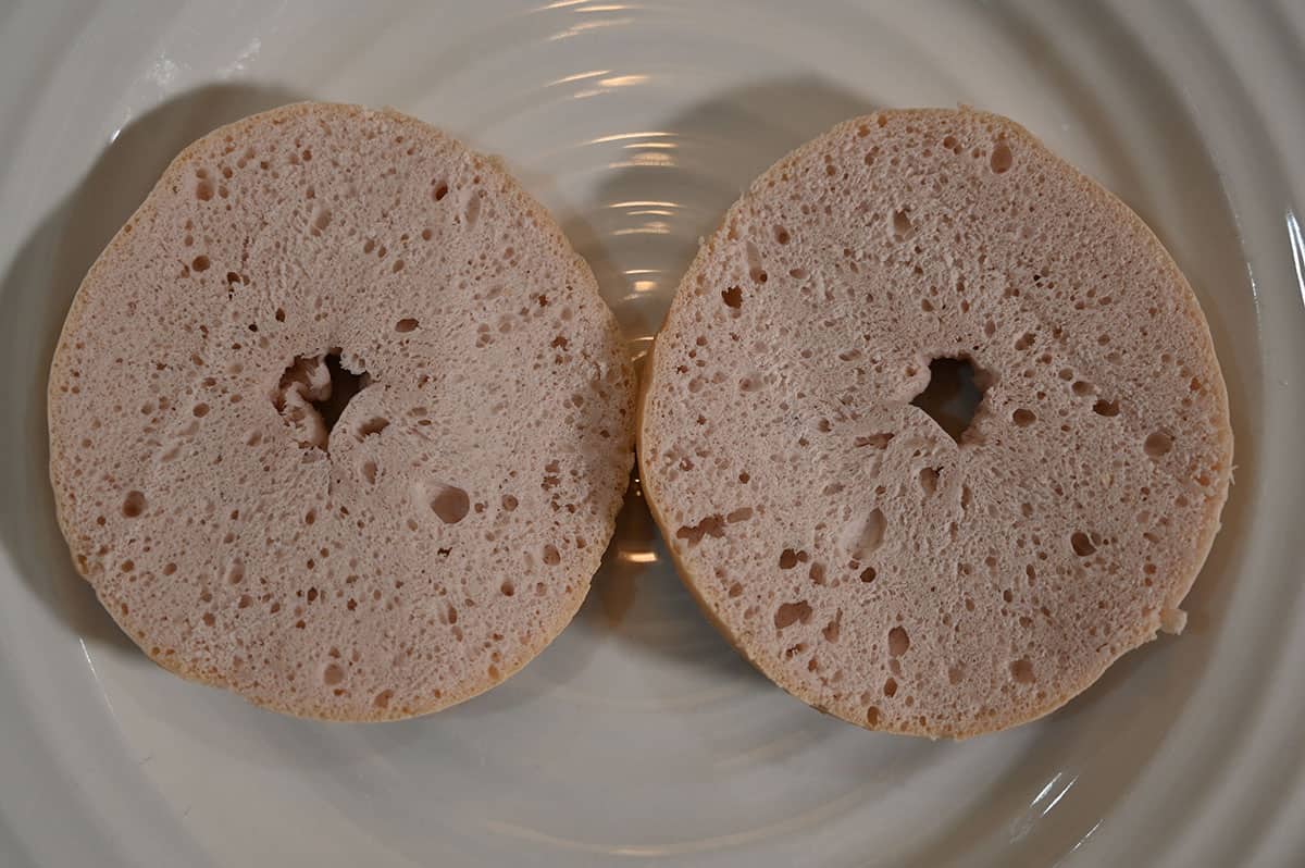 Image of a bagel cut in half and served on a white plate.
