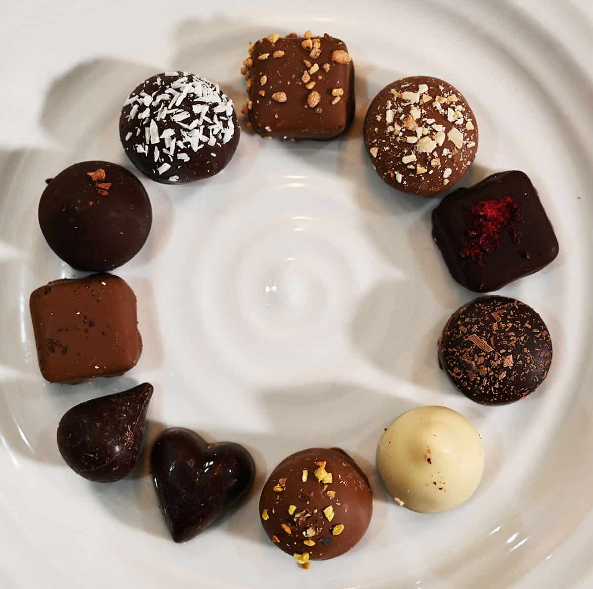 Image of all 11 chocolates in a circle on a white plate.